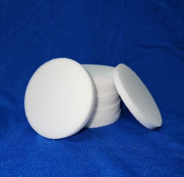 A stack of white round coasters on top of blue cloth.